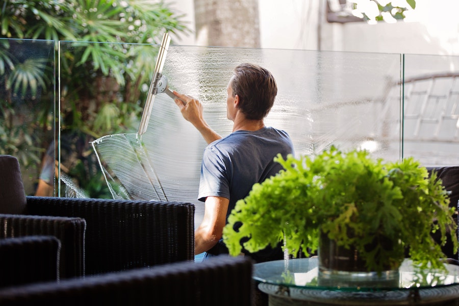 Mann reinigt Fensterscheibe mit Abziehen